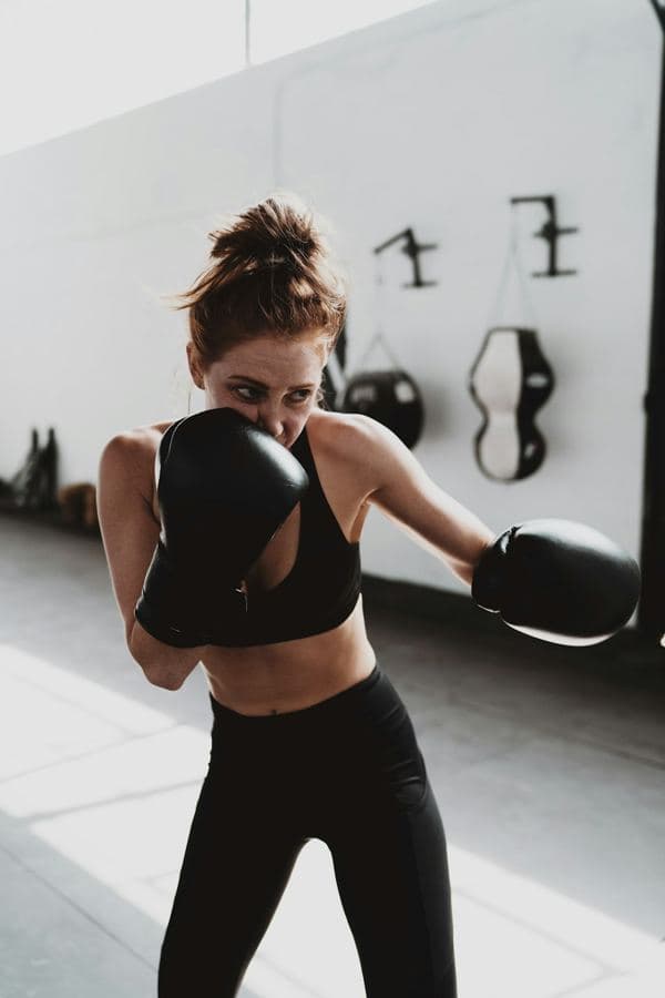 A woman boxing in a bright, white gym
