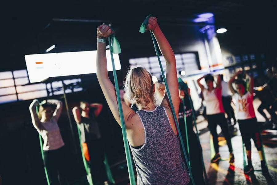 A group class working with resistance bands under coloured lights