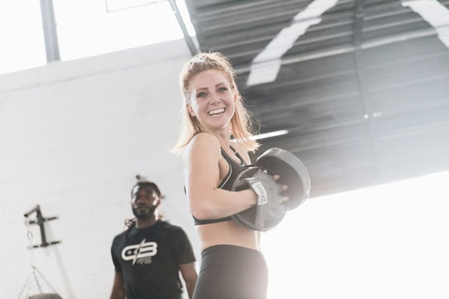 A coach laughing, pad in hand, in a bright gym